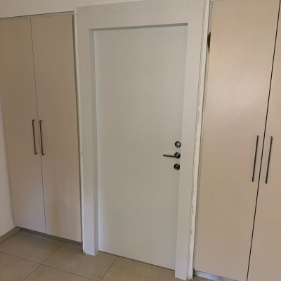 דלת לבנה בין ארונות עם ידיות מתכת