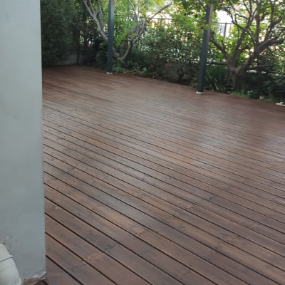 רצפת עץ עם פרגולה וגינה ברקע