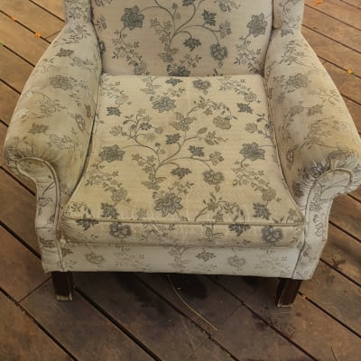 כורסה עם דוגמת פרחים על רצפת עץ, צינור ניקוי ליד