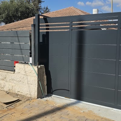 גדר מתכת אפורה ליד שביל מרוצף באבנים