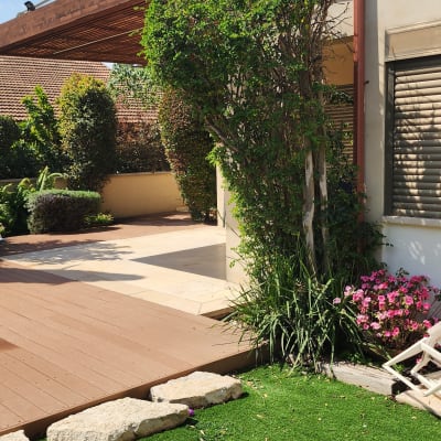 פרגולה מעץ בחצר עם דשא סינטטי ומגלשה אדומה