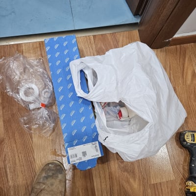 כלי עבודה וחומרים על רצפת עץ, כולל מקדחה ונעל עבודה