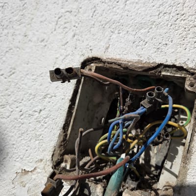 חוטי חשמל חשופים בקופסת חיבורים על קיר