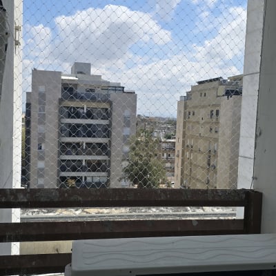 רשת יונים מותקנת על מרפסת עם נוף לבניינים