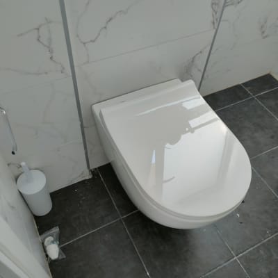 אסלה תלויה עם מברשת שירותים על רצפת אריחים