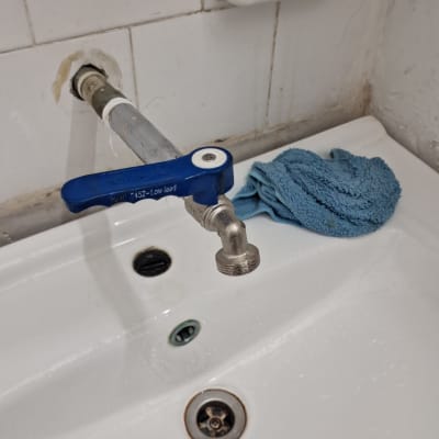 ברז עם ידית כחולה על כיור לבן