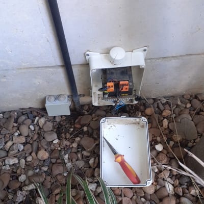 ארון חשמל פתוח עם חוטים ומברג על הקרקע