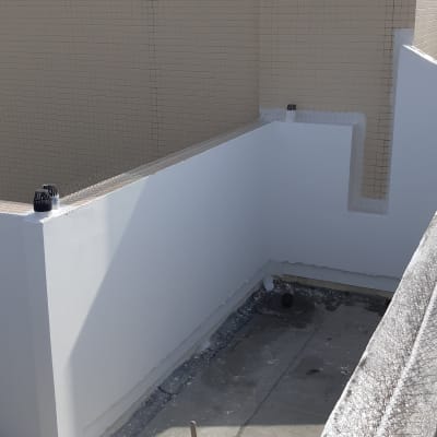 אדם צובע קיר חיצוני בלבן עם מברשת ארוכה