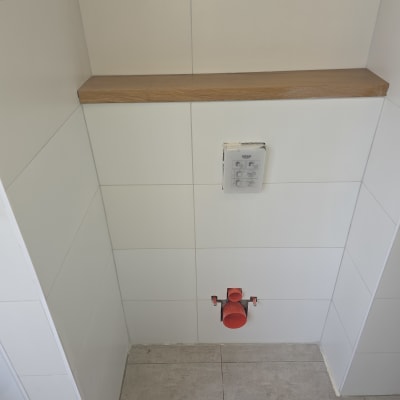 צנרת אדומה בקיר לבן עם מדף עץ