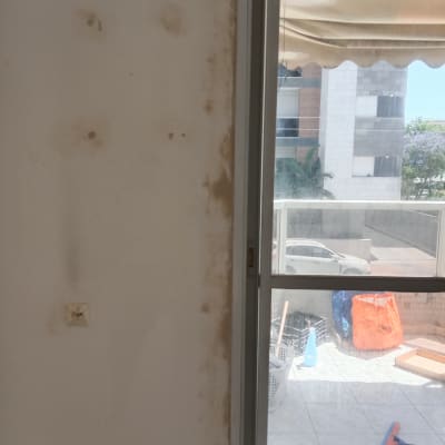 קיר עם סימני תיקון ליד חלון ומרפסת