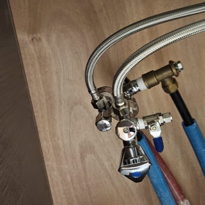 צינורות מים מתכתיים וברזים מתחת לכיור