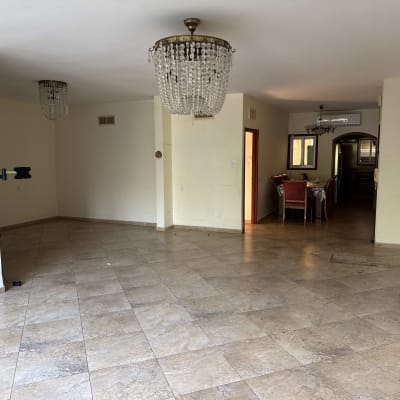 חדר ריק עם רצפת אריחים, נברשות ומטאטא בפינה