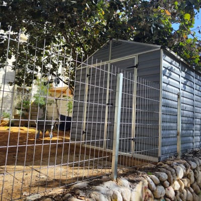 גדר מתכת סביב מחסן אפור עם גג משופע