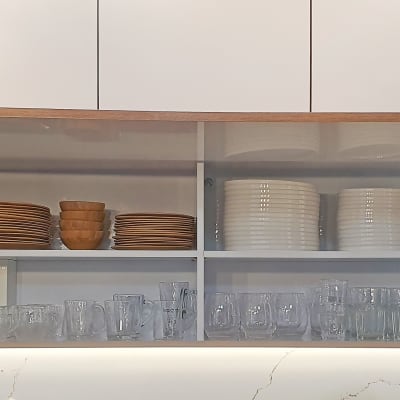 ארון מטבח פתוח עם צלחות, כוסות וספלים מסודרים