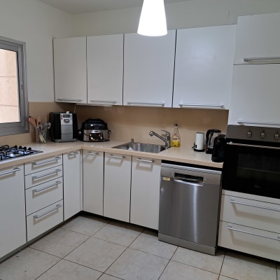 מטבח מאורגן עם ארונות לבנים ומכשירי חשמל