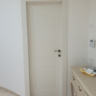 דלת לבנה עם ידית מתכת על קיר לבן