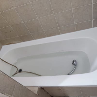 אמבטיה עם מים וצינור מתכת, קיר מחופה אריחים