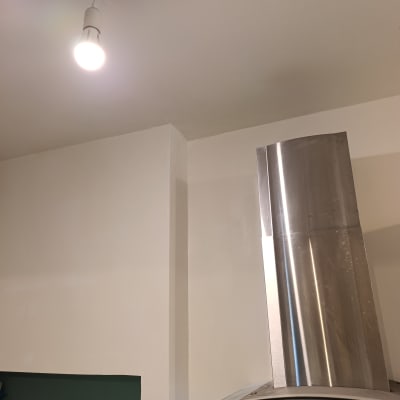 קיר צבוע עם מנורה ומכסה נירוסטה במטבח