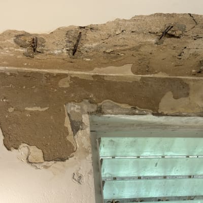 נזקי בטון וטיח בתקרה ובקיר עם ברזלי זיון חלודים