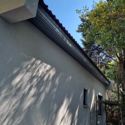 גג רעפים עם קיר חיצוני ועצים ברקע