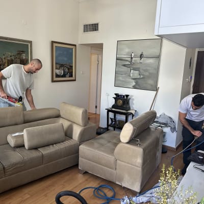 שני אנשים מנקים ספות עם מכשירים חשמליים