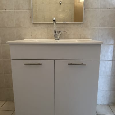 כיור עם ברז ומראה על קיר אריחים