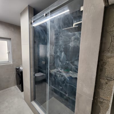 מקלחון זכוכית בחדר אמבטיה מודרני עם קירות אפורים