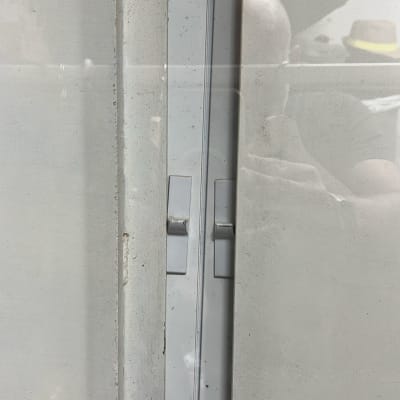 תריסים לבנים עם ידיות מתכת על קיר לבן