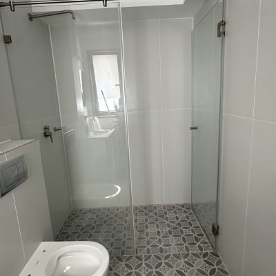 מקלחון זכוכית עם דלתות שקופות ורצפת אריחים מעוצבת