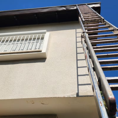 סולם מתכת נשען על גג בית