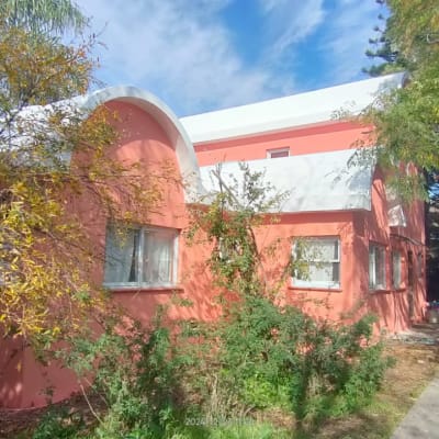 בניין ורוד עם גג לבן ועצים מסביב