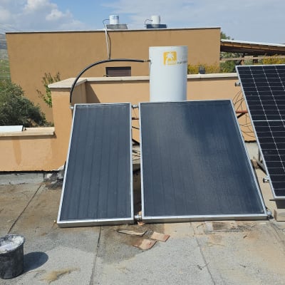 דוד שמש עם קולטים על גג תחת שמיים כחולים