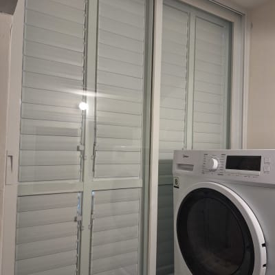 חלון אלומיניום עם תריסים ליד מכונת כביסה