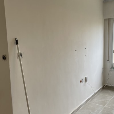 קיר צבוע בלבן עם מוט צביעה על הרצפה