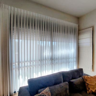 וילון לבן תלוי מעל ספה אפורה בחדר מגורים