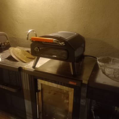 תנור אפייה קטן עם ידית כתומה על משטח עבודה