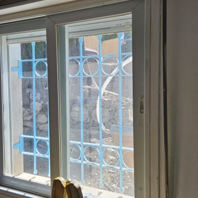 חלון עם תריס פתוח ומעקה כחול בחוץ