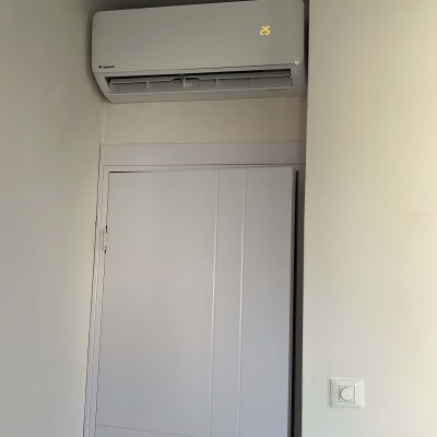 מזגן מותקן על קיר מעל דלת, מציג טמפרטורה 25 מעלות