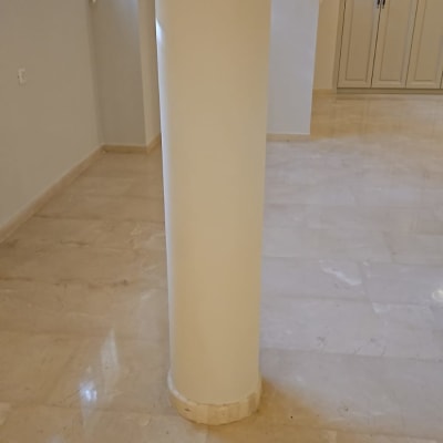 עמוד עגול צבוע בלבן על רצפת שיש