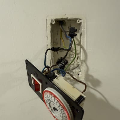 שעון טיימר חשמלי עם חוטים חשופים בקיר