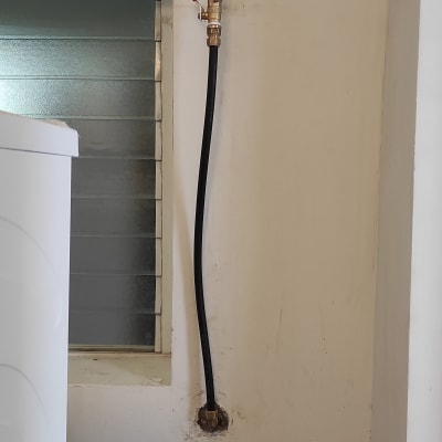 צינור מים עם ברז אדום על קיר לבן