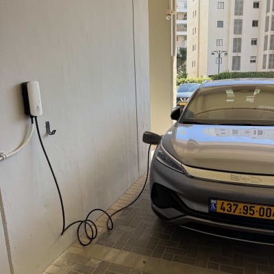 רכב חשמלי מחובר לעמדת טעינה בקיר