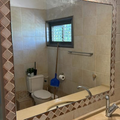 מראה גדולה עם מסגרת אריחים בחדר אמבטיה