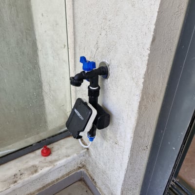 ברז מים עם מערכת השקיה אוטומטית על קיר חיצוני