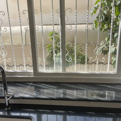 כיור נקי ליד חלון עם סורגים וצמח בחוץ