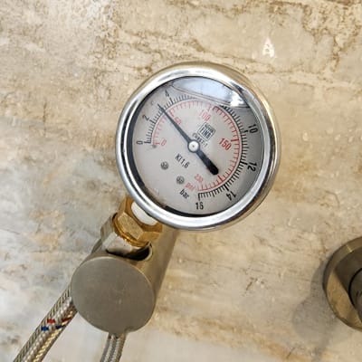 מד לחץ מחובר לצינור על קיר רטוב