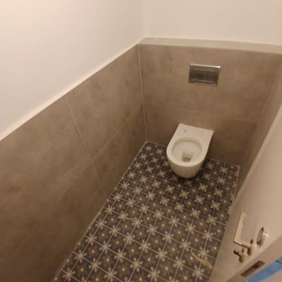 חדר שירותים משופץ עם אסלה תלויה, חיפוי קיר וריצוף מצויר
