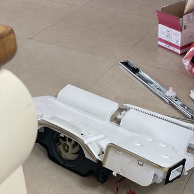 חלקי מקרר מפורקים על הרצפה עם מאוורר וחוטים