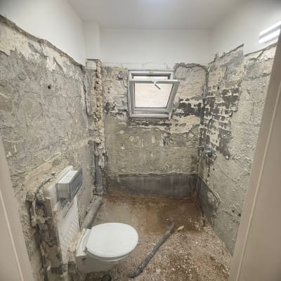 חדר אמבטיה בשיפוץ עם קירות חשופים ואסלה מותקנת