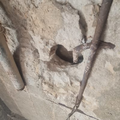 תמונה של קיר עם חור וברזלים חשופים